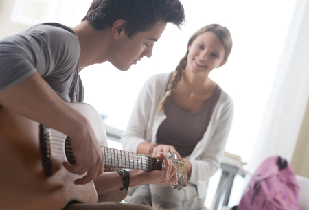 Young handsome man playing guitar for his girlfriendの写真素材