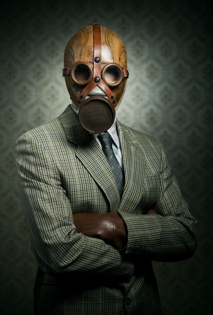 Vintage businessman wearing a gas mask with retro wallpaper on background.の写真素材