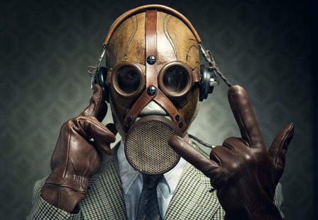 Man wearing gas mask and headphones making rock sign.の写真素材