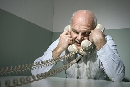 Stressed overworked businessman talking on the phone, vintage style.の写真素材