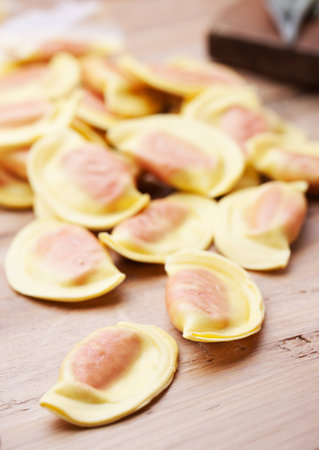 Handmade ravioli with red filling on wooden table.の写真素材