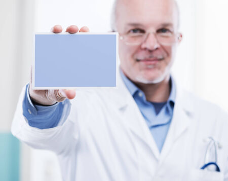 Doctor showing a small white sign, a custom message can be added.の写真素材