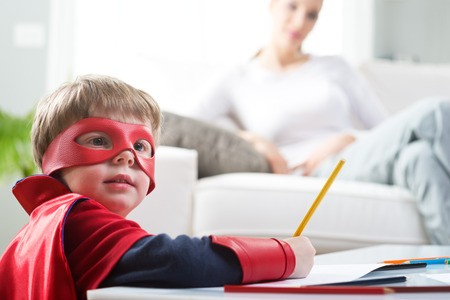 Mother and super hero boy spending time together at home.の写真素材