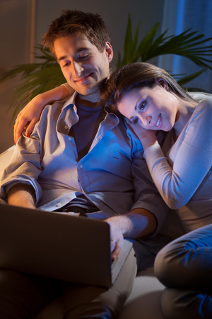 Young couple relaxing and enjoying at home on sofa with laptop.の写真素材