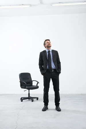 Smiling businessman standing in his new empty office with hands in pockets looking around.の写真素材