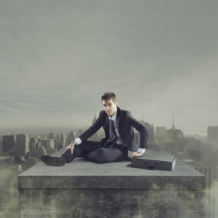 Young businessman falling to the ground with post apocalyptic cityscape on background.の写真素材
