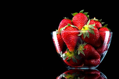 Delicious strawberries in a glass bowl on black background.の写真素材