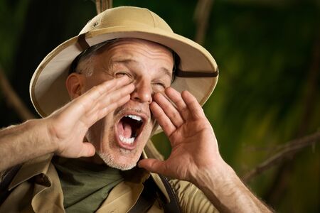 Adventurer shouting out loud in the jungle with hands cupped around mouth.の写真素材