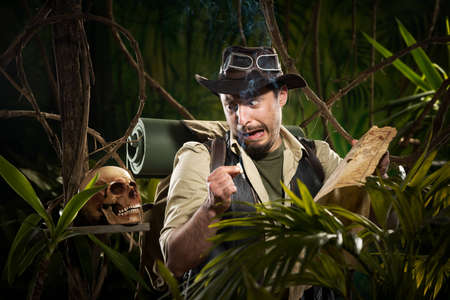 Explorer with map smoking in the jungle and finding a human skull.の写真素材