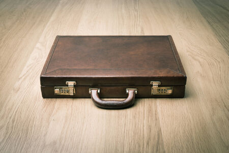Leather vintage briefcase on hardwood floor with safety lock.の写真素材