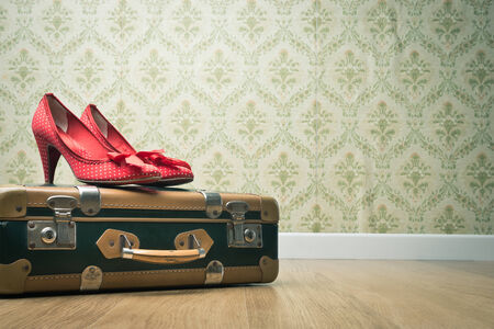Female red dotted shoes with vintage suitcase on floor and retro wallpaper.の写真素材