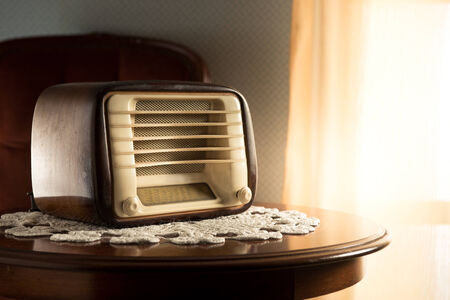 Vintage radio on round table with doily and living room on background.の写真素材