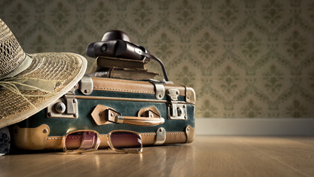 Vintage luggage with sunglasses, camera and straw hat on wooden floor.の写真素材