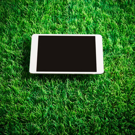 Digital touch screen tablet with copyspace on green artificial turf.の写真素材