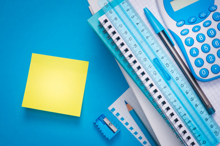 Yellow stick note with stationery on light blue background.の写真素材