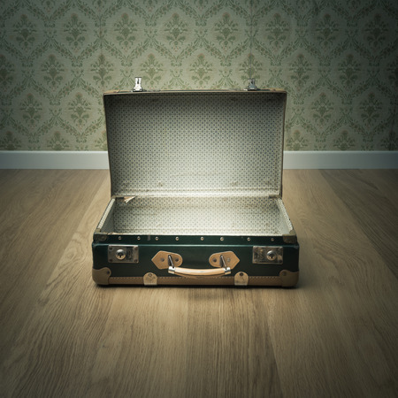Open vintage suitcase on wooden floor with vintage wallpaper on background.の写真素材
