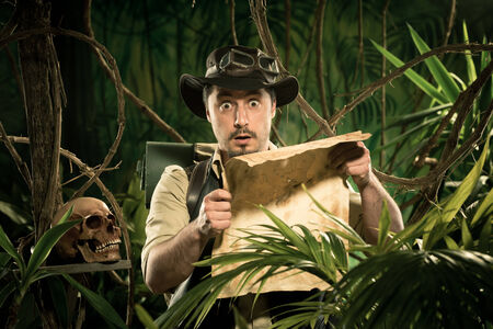 Young explorer lost in jungle examining an old map.