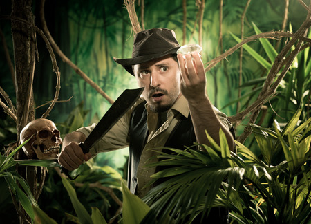 Adventurer with machete finding a huge gem in the jungle with skull on foreground.の写真素材