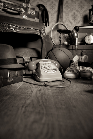 Group of vintage objects on attic hardwood floor, including old toys, phone and sports items.の写真素材