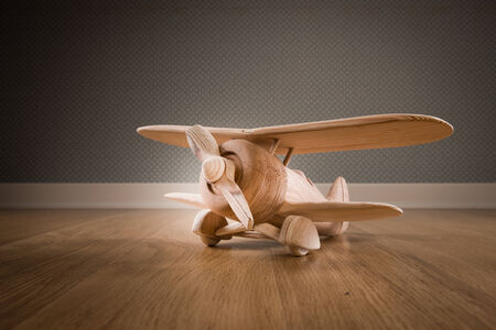 Wooden toy plane hand carved model on hardwood floor.の写真素材