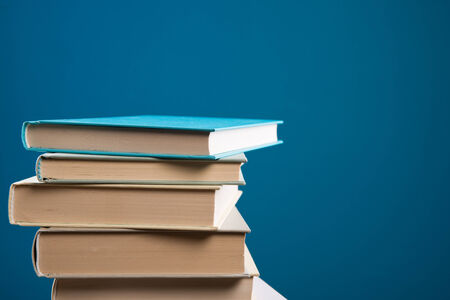 Pile of hardcover books on blue background