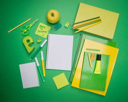 Back to school with green and yellow stationery and stick note.