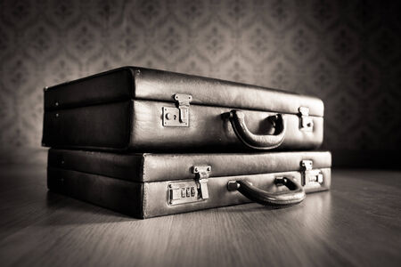 Stack of leather briefcases with vintage wallpaper background.の写真素材