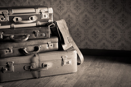 Pile of leather vintage suitcases, retro wallpaper on background.の写真素材