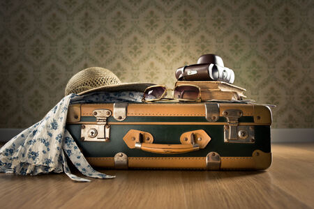 Vintage luggage with sunglasses, camera and straw hat on wooden floor.の写真素材