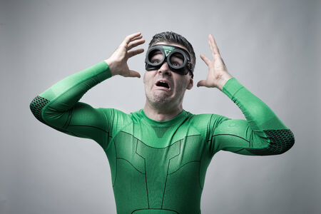 Terrified funny superhero in green costume with raised hands.の写真素材