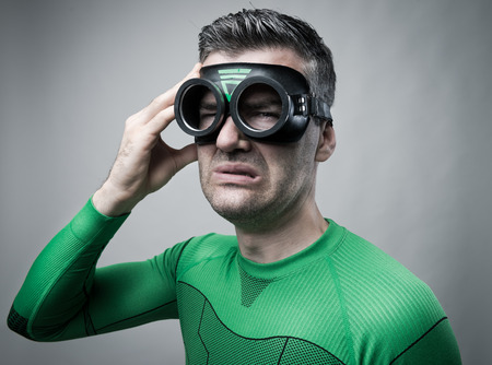 Sad suffering superhero with strong headache touching his head.の写真素材