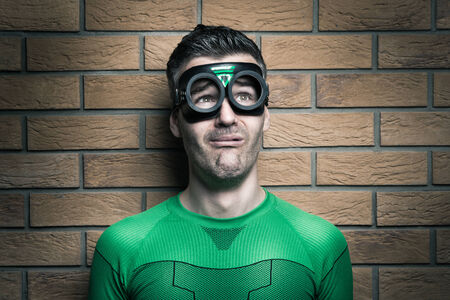 Terrified green superhero looking away and leaning to a wall.の写真素材