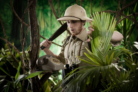 Young explorer with machete finding a vintage telephone in the jungle.
