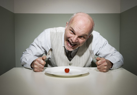 Vintage style insane man having a sad dinner alone.の写真素材