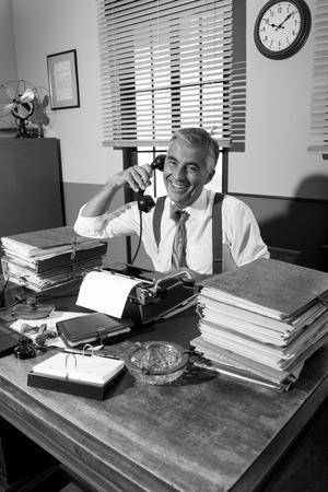 Vintage professional journalist on the phone working at office desk.
