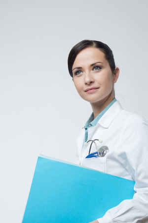 Smiling young female doctor holding medical records file.の写真素材