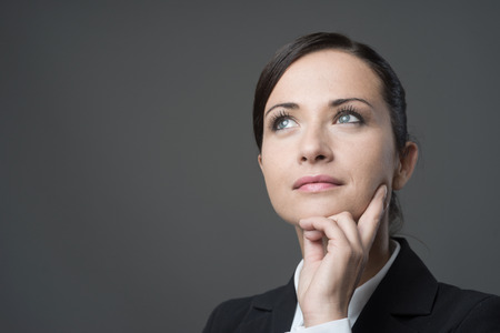 Attractive pensive business woman with hand on chin looking away.の写真素材