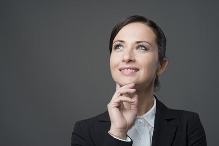 Smiling charming business woman with hand on chin looking away.の写真素材
