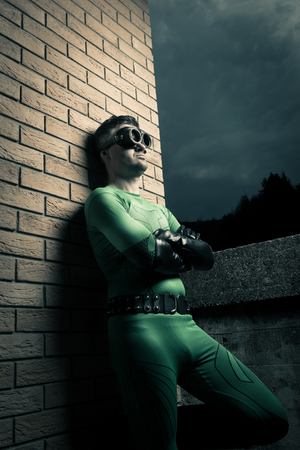 Cool superhero with arms crossed leaning to a brick wall.の写真素材