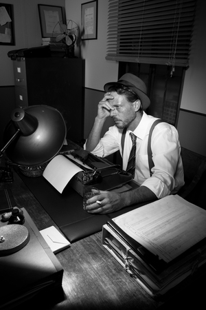 Exhausted reporter working late at night, smoking and drinking.の写真素材