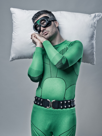 Superhero sleeping on a pillow floating in the air with hands clasped.の写真素材