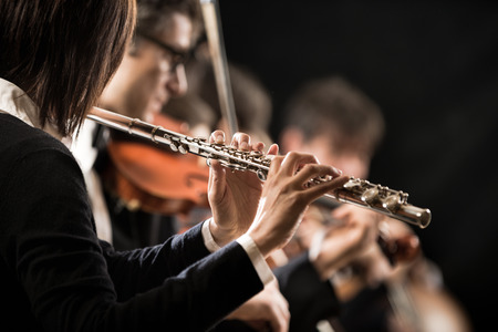 Female flutist performing, hands close-up on dark background.の写真素材