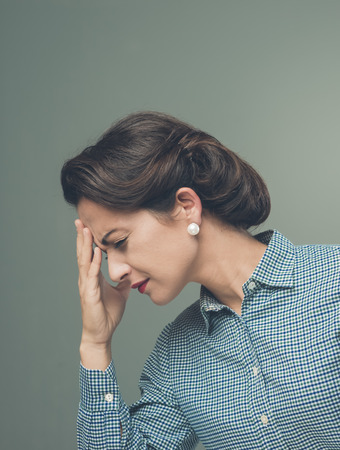 Vintage woman with headache touching her foreheadの写真素材