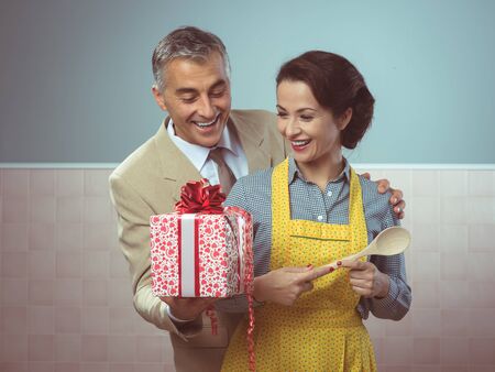 Vintage romantic couple at home, he is giving to his wife a beautiful surprise giftの写真素材