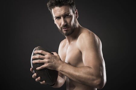 Shirtless confident footbal player holding ball and showing his muscular bodyの写真素材