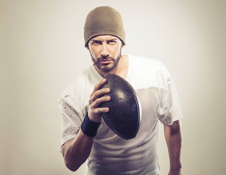 Handsome muscular football player holding ball and posingの写真素材
