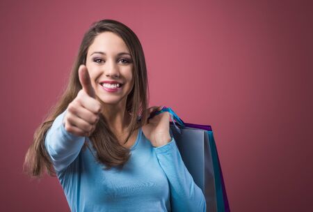 Happy smiling woman thumbs up shopping and holding bagsの写真素材