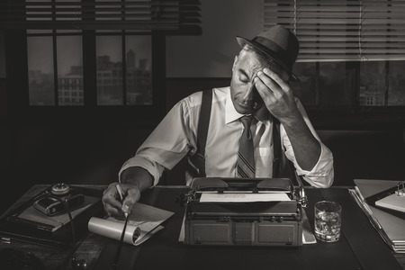 Professional reporter working late at night at his desk with vintage typewriter, 1950s style.