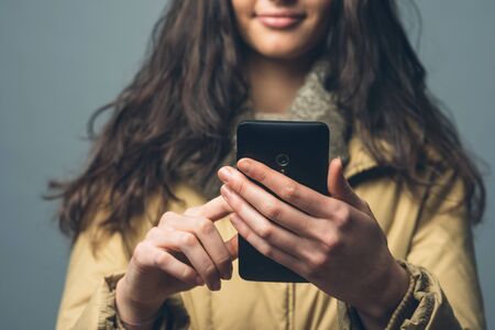 Smiling beautiful woman with smart phone text messagingの写真素材