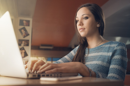Busy young woman using a laptop and staring at computer screenの写真素材